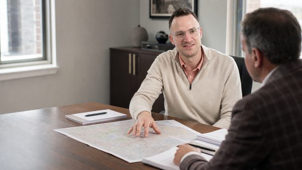 An adviser and a business owner reviewing printed plans together across a boardroom table